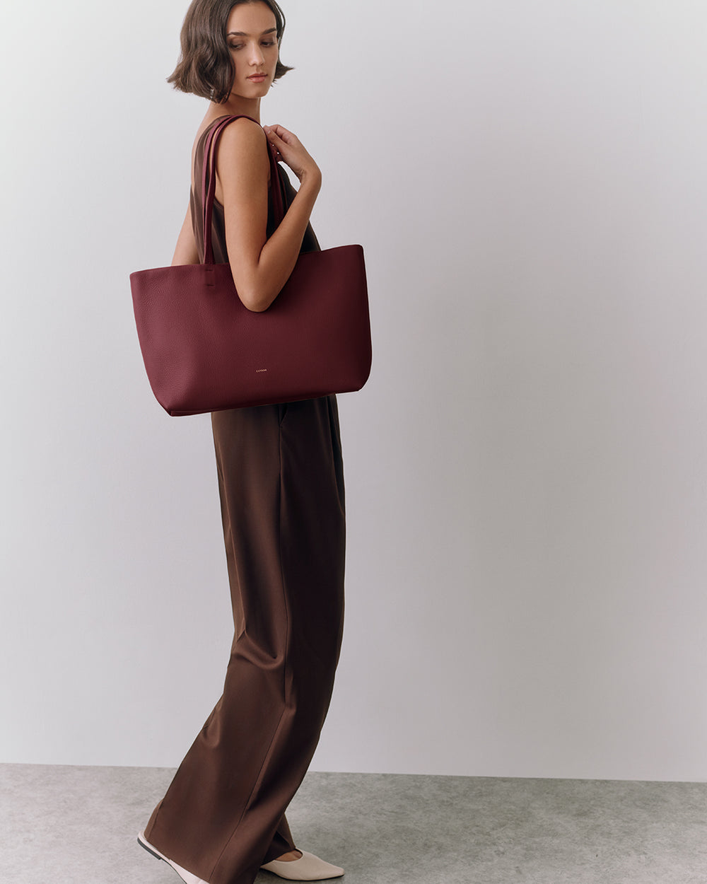 Small Easy Tote Person wearing a sleeveless top and pants, holding a tote bag.