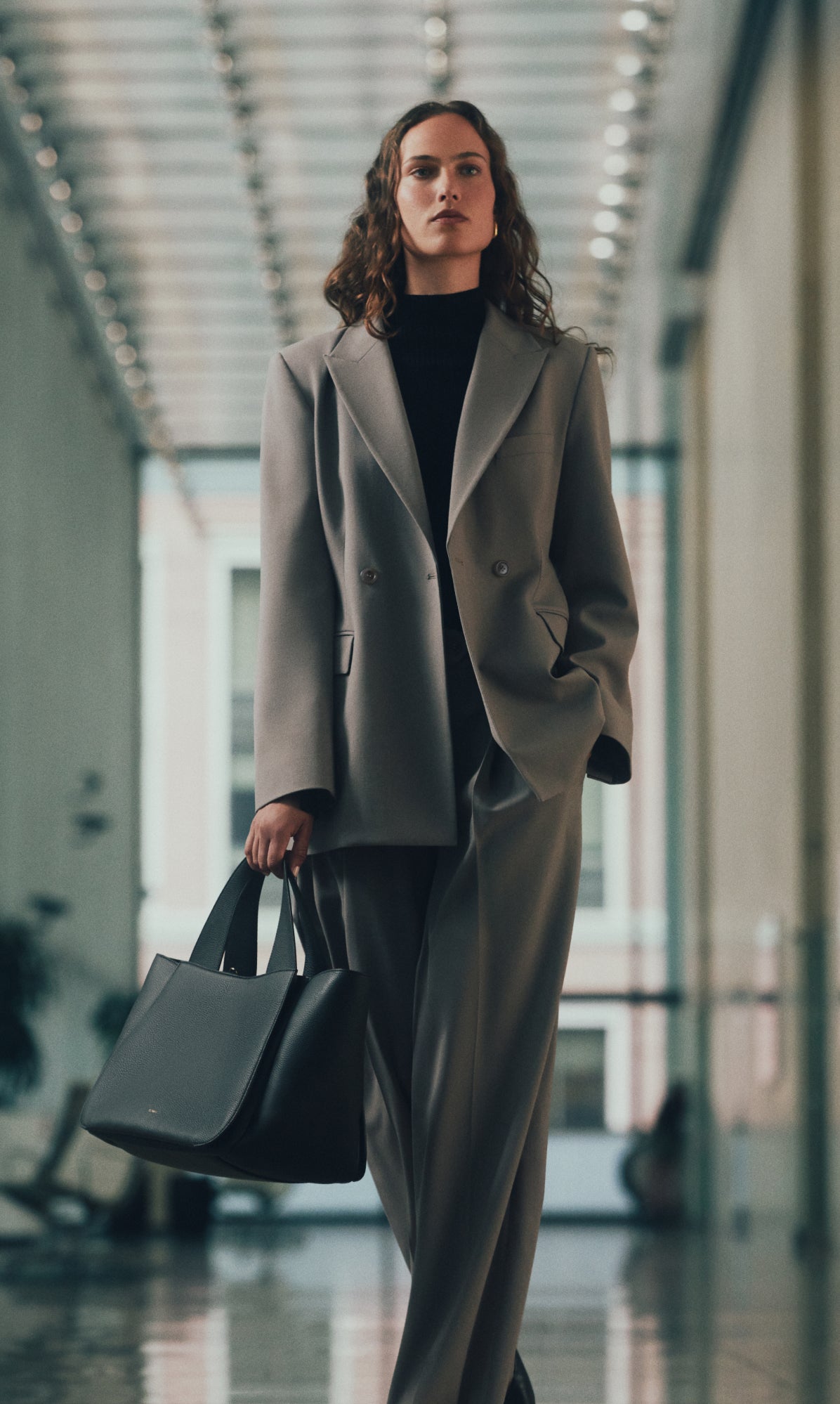 Person in a suit walking in a hallway holding a large bag