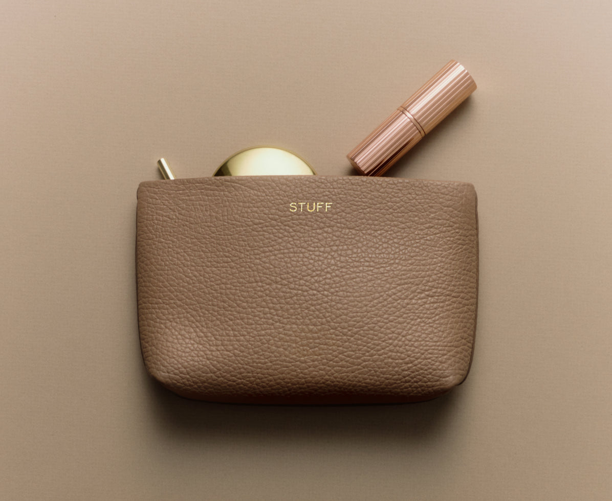 Pouch with a compact and a lipstick partially inside.