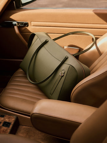 Travel bag on car seat with straps and zipper visible.