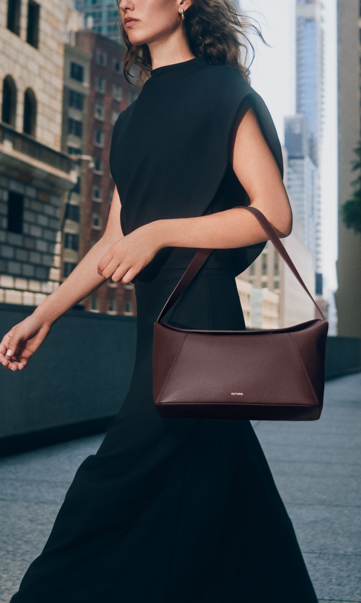 Person walking in a city holding a handbag.