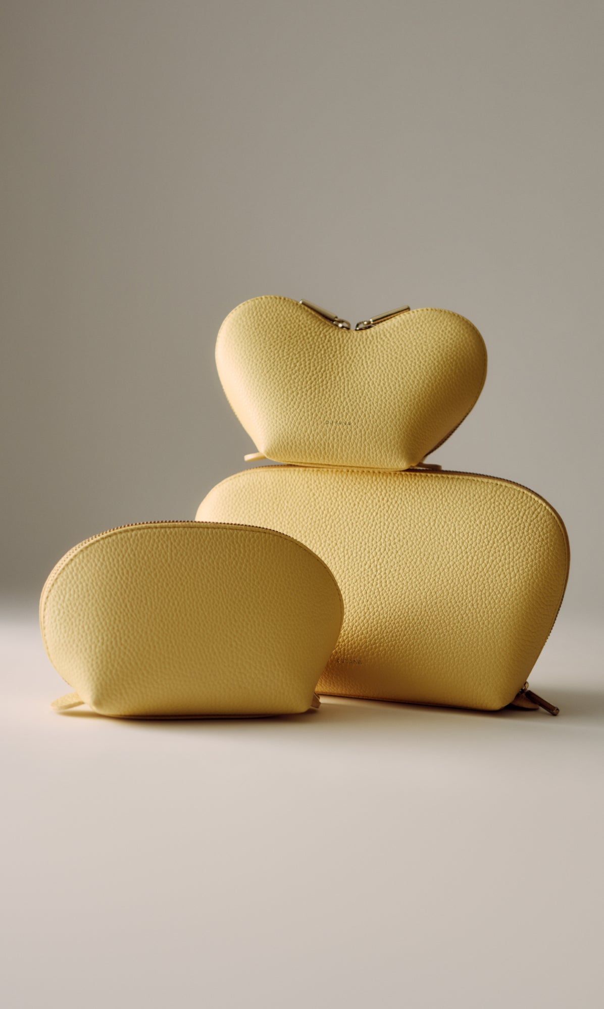 Three zippered pouches in different shapes and sizes arranged on a surface.