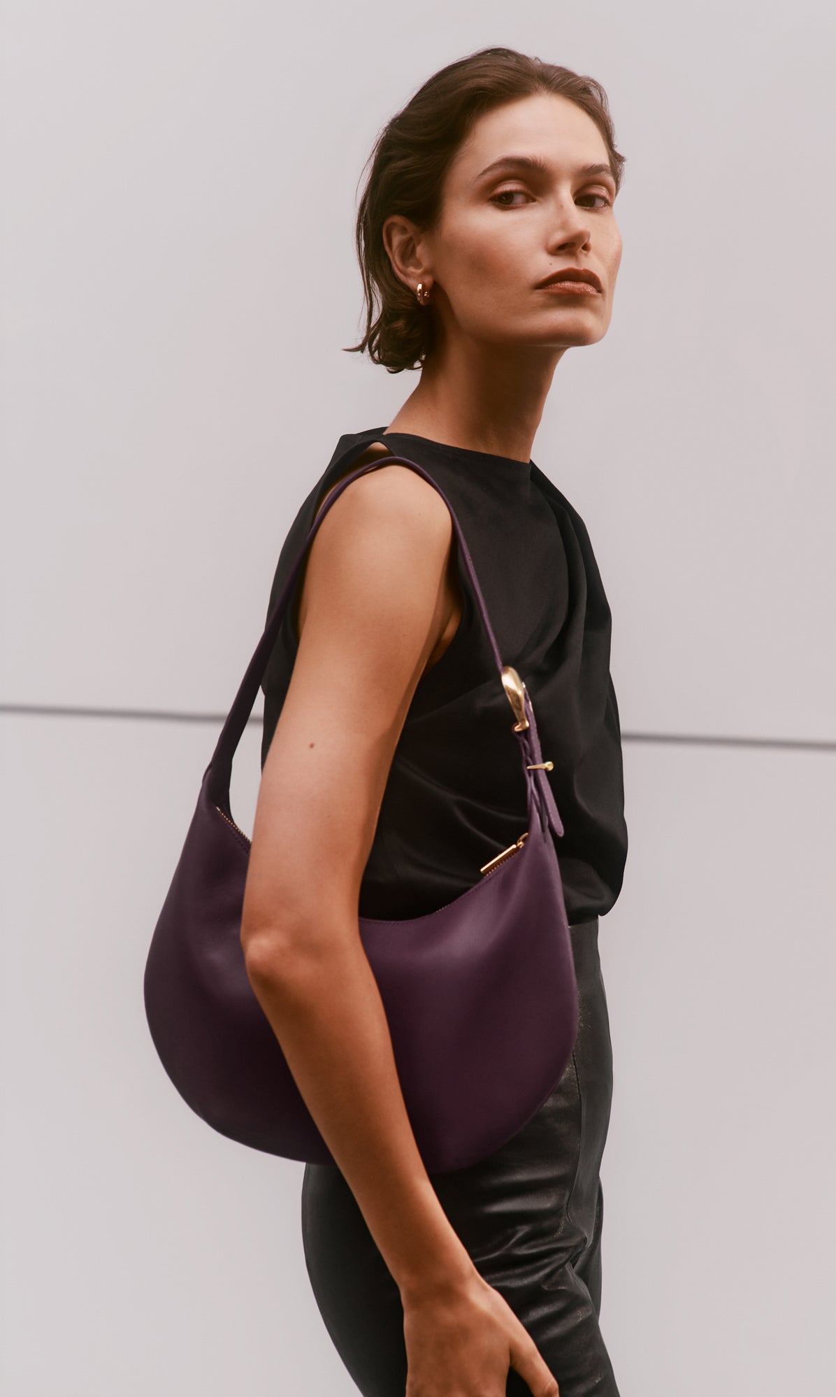 Person wearing a sleeveless top and holding a handbag