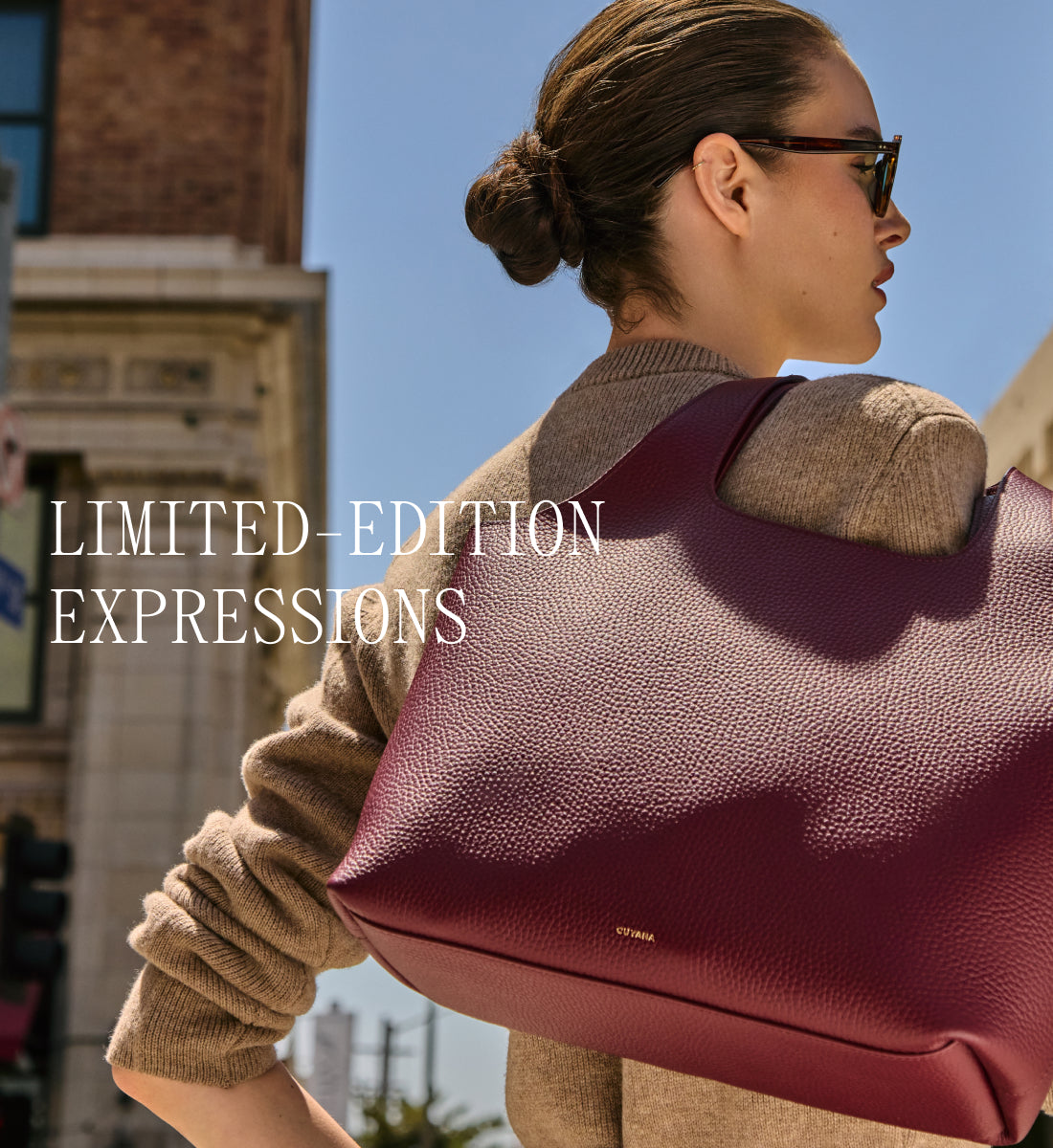 Person wearing sunglasses holding large textured handbag over shoulder.