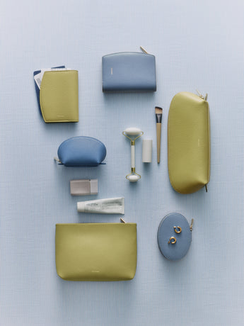 Assorted pouches, wallets, makeup bags, and beauty tools arranged on a flat surface.