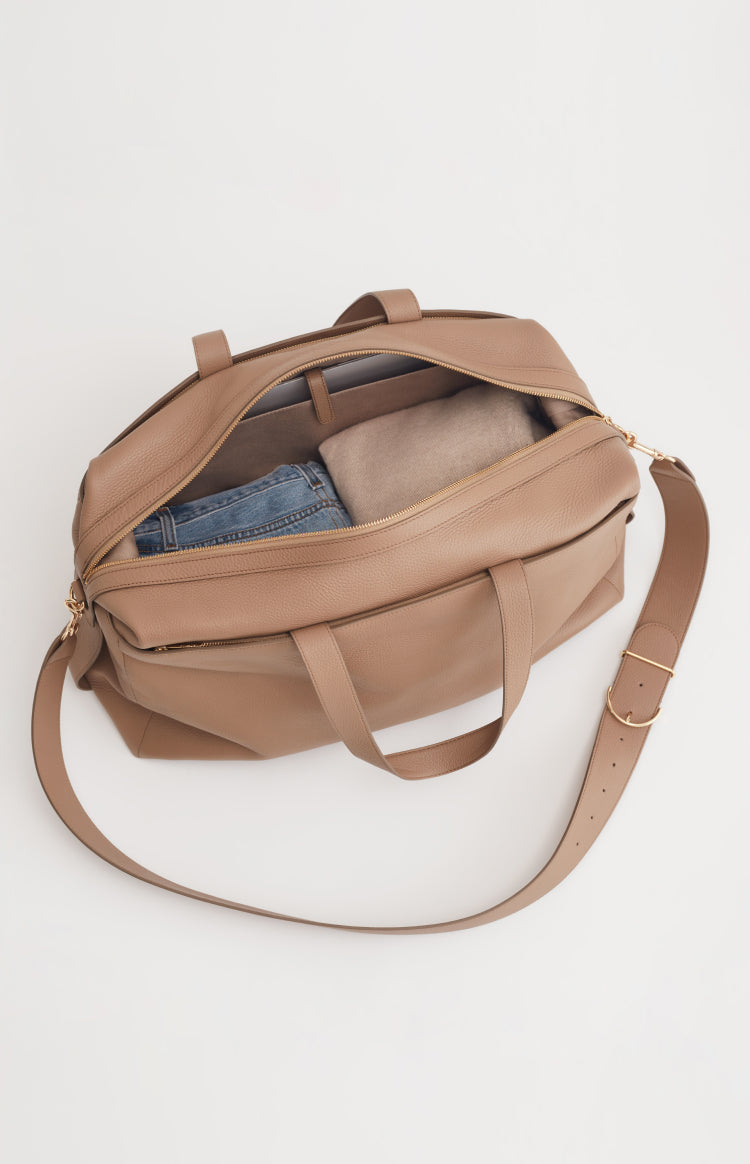 Open bag with a strap, containing a pair of jeans.