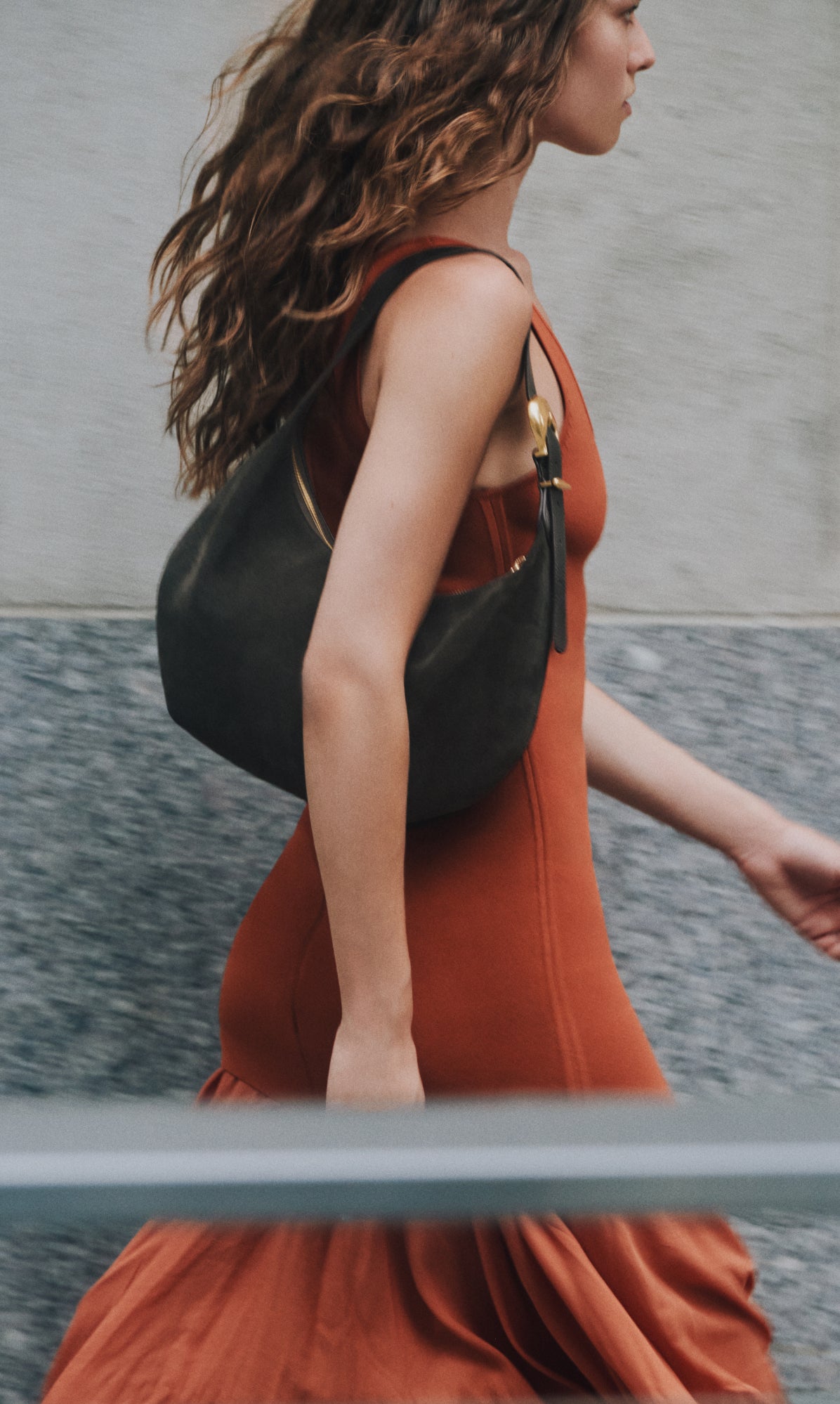 Person walking with a shoulder bag wearing a flowing sleeveless dress