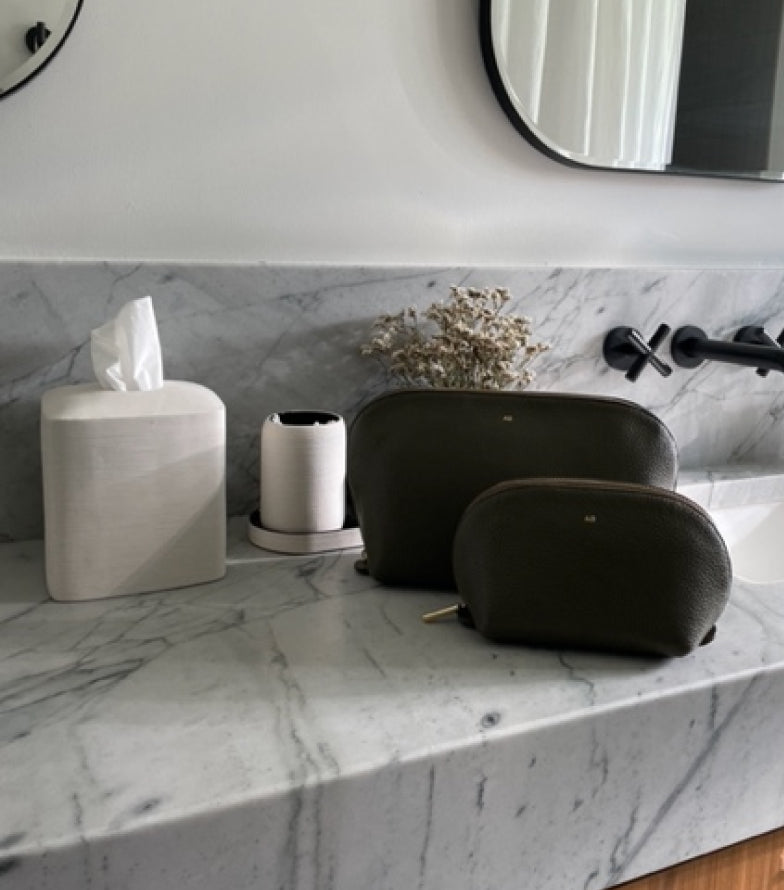 Bathroom counter with a tissue box, toilet paper, and two bags.
