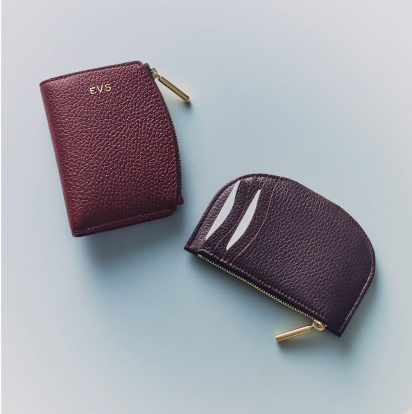 Two textured leather wallets with zippers on a flat surface.