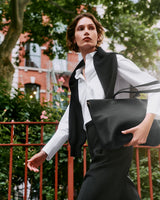 Person walking outdoors carrying a travel bag and wearing a jacket over shoulders