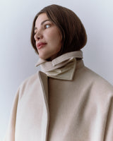 Person wearing a coat with a high collar looking to the left