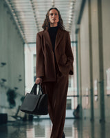 Person in suit holding a handbag walking in a building corridor.