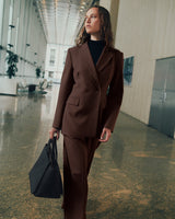 Person in a suit carrying a bag walking in a spacious hallway.