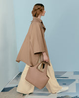 Woman walking in a modern setting while carrying a large bag.