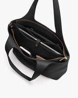 Open handbag with various items inside, including a laptop and a phone.