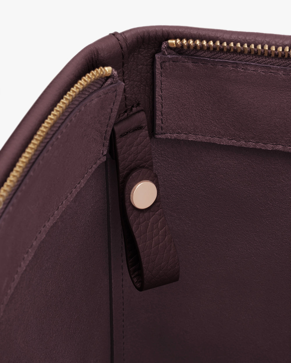 Close-up of a leather bag's interior with a zipper and a buttoned strap.