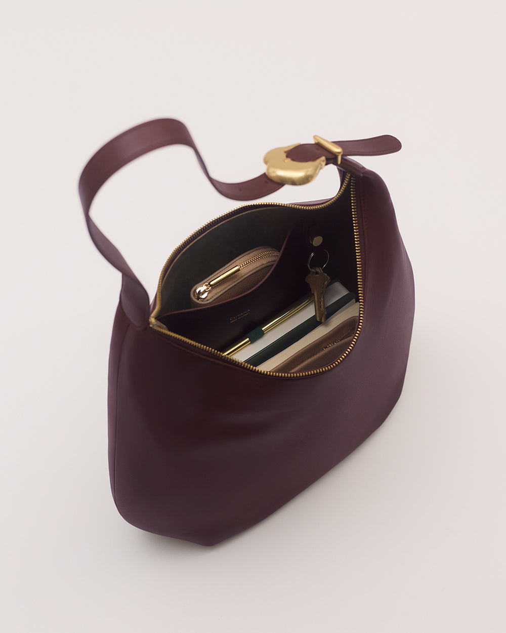 Open handbag with keys, phone, and notebook inside.