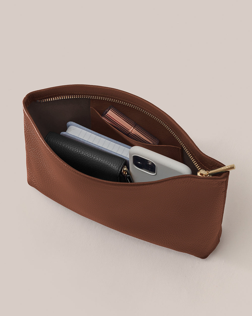 Open pouch with phone, wallet, notebook, and lipstick inside