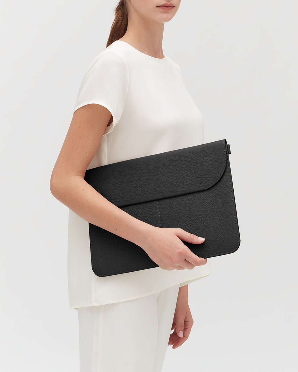 Person holding a large leather laptop sleeve
