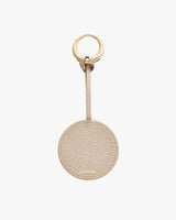 Round keychain with a textured leather finish and a gold-colored ring at the top
