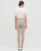 Woman seen from behind wearing a fitted top and leggings, standing upright.