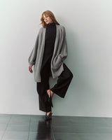 Person wearing long cardigan, black pants, and heels.