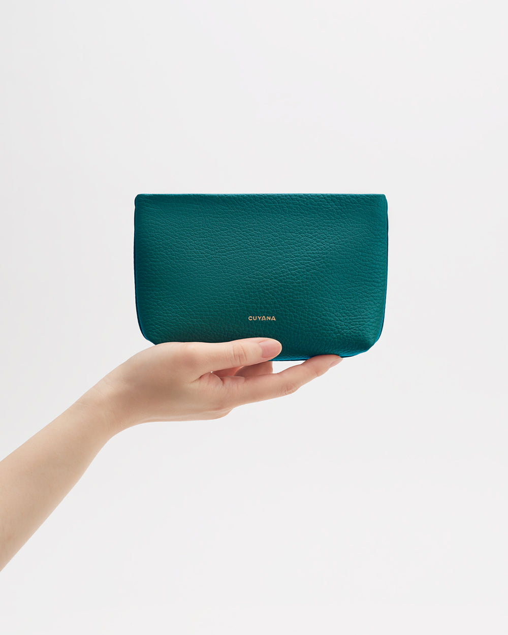 A hand holding a small textured pouch against a plain background.