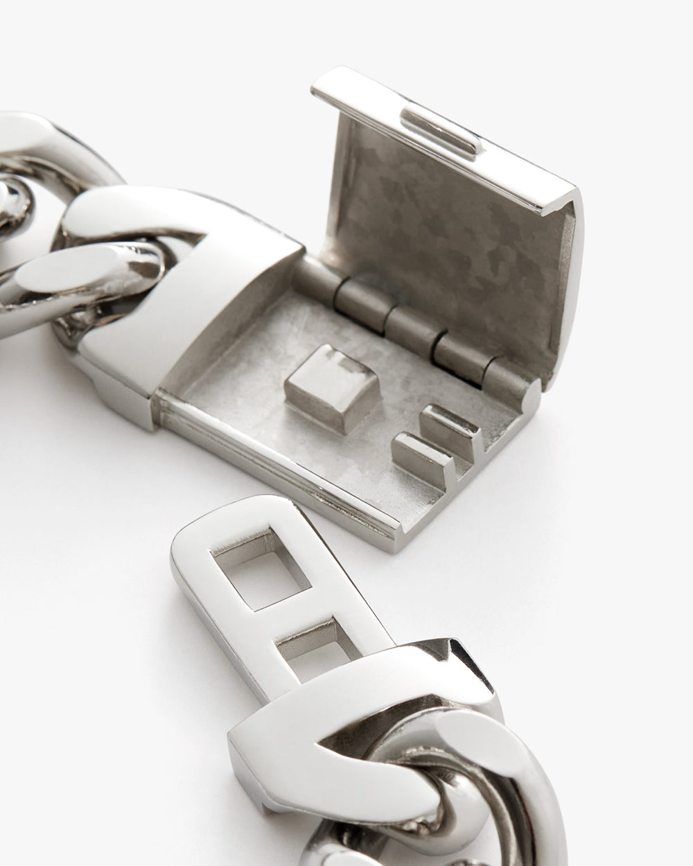 Close-up of an open metal clasp linked to a chain.