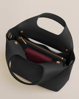 Open handbag showing pockets and zippers with contents inside.