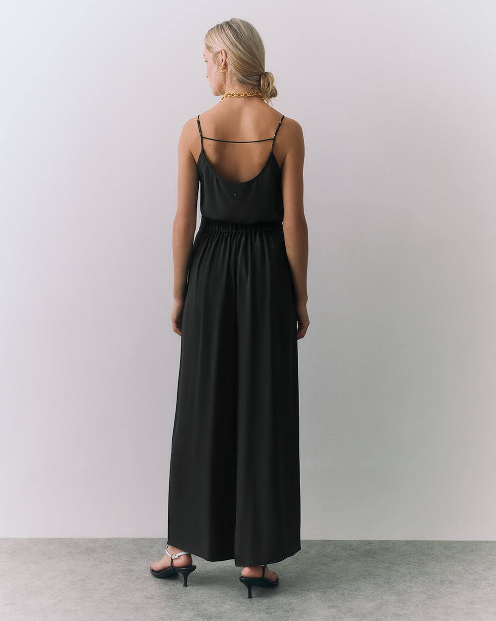 Person in a silk cami and wide leg pants, facing away from the camera.