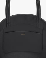 Close-up of a handbag with two handles and a front pocket.
