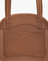 Close-up view of a handbag with a brand logo on the front pocket.