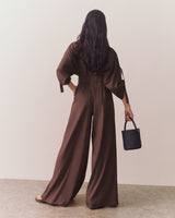 Person wearing wide leg pants holding a small croc-embossed leather bag