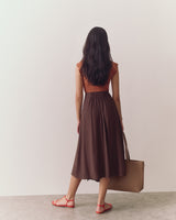 Person wearing a T-shirt and skirt, facing away, standing on a plain floor.