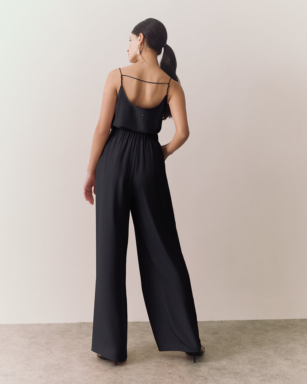 Woman walking in sleeveless top and wide-leg pants.
