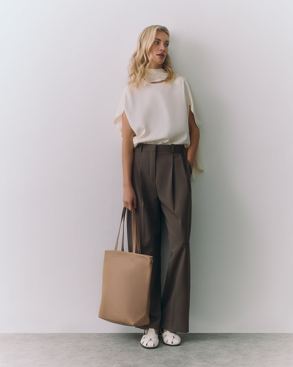 Person in a sleeveless top and pants holding a tote bag.