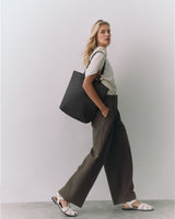 Person wearing a white shirt, wide pants, sandals, and carrying a large shoulder bag.