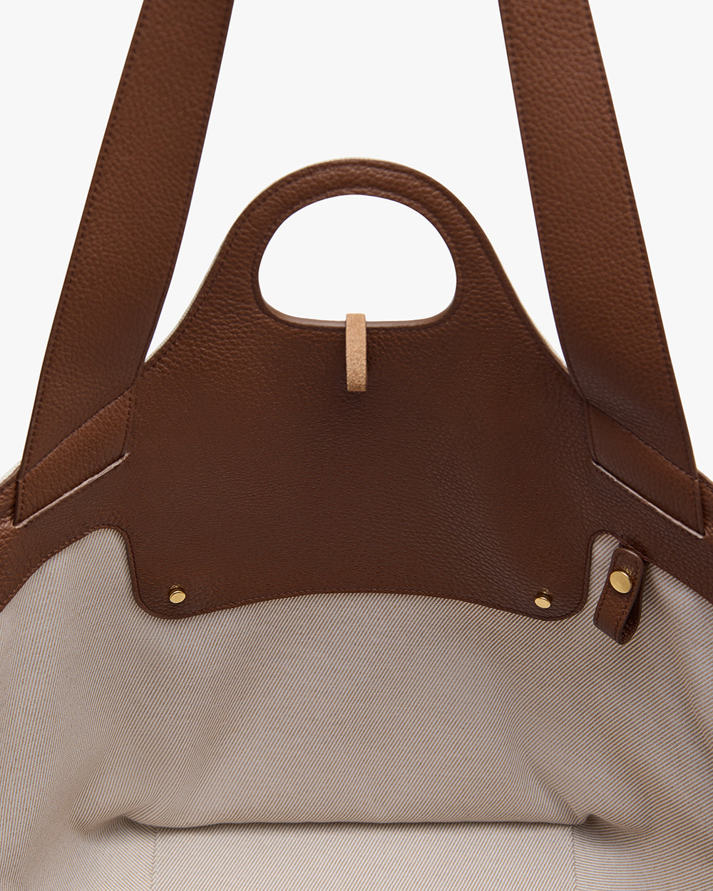 Open leather tote bag with a handle showing the interior fabric lining.