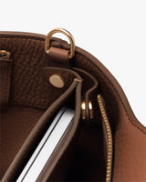 Bag interior with a zipped pocket, a laptop sleeve button, and a gold loop detail.