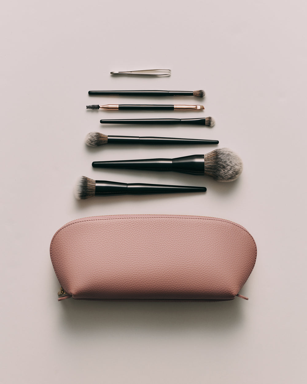 Makeup brushes and tools arranged above a cosmetic bag.