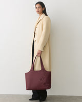 Person wearing long coat holding a large bag with floral patterns
