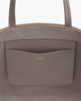 Tote bag with top handles and pocket featuring logo.