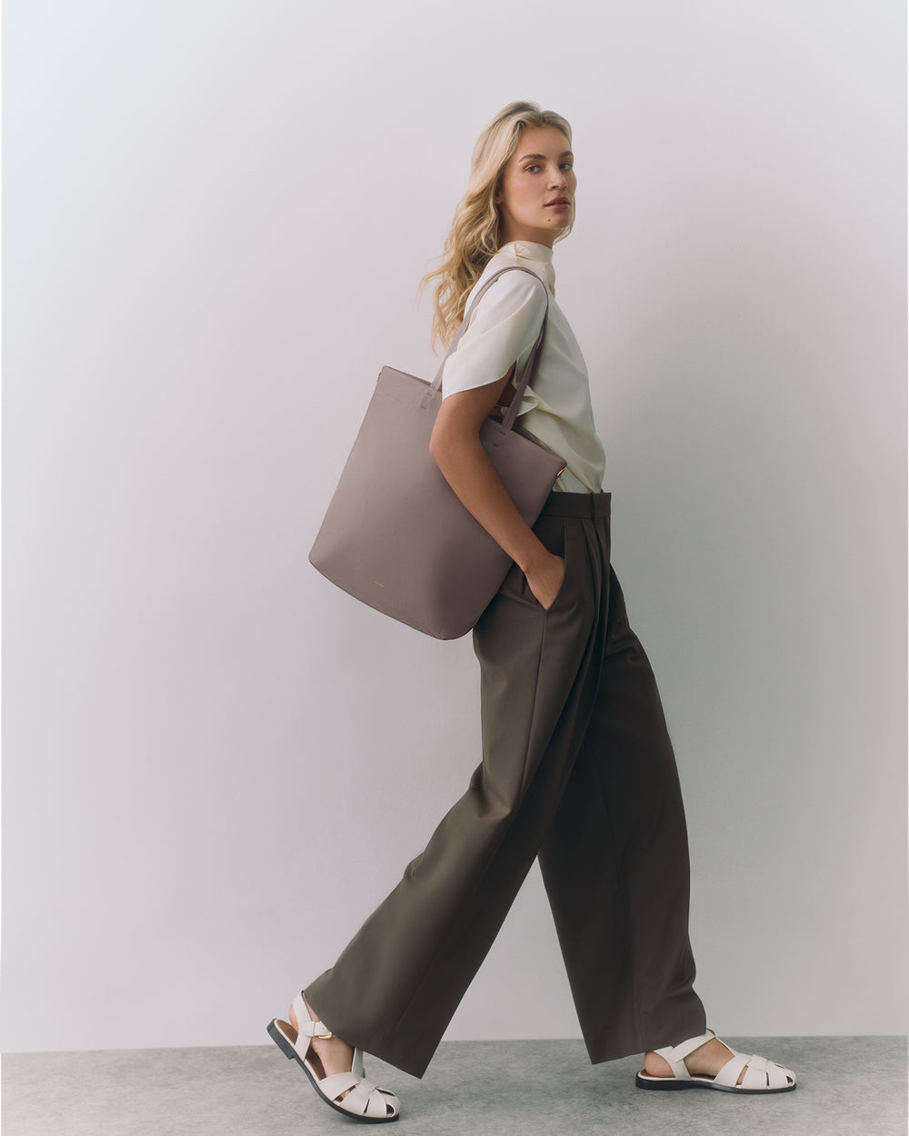 Person carrying a large tote bag while walking.