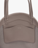 Round handbag with two handles and a pocket on the front.