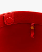Open tote bag with a round button and a strap inside.