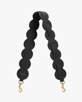 Bag strap with circular segments and gold clasps.