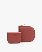 Two small wallets, one with a zipper, stand upright.