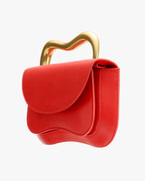 Handbag with wavy flap and unique curved handle design.