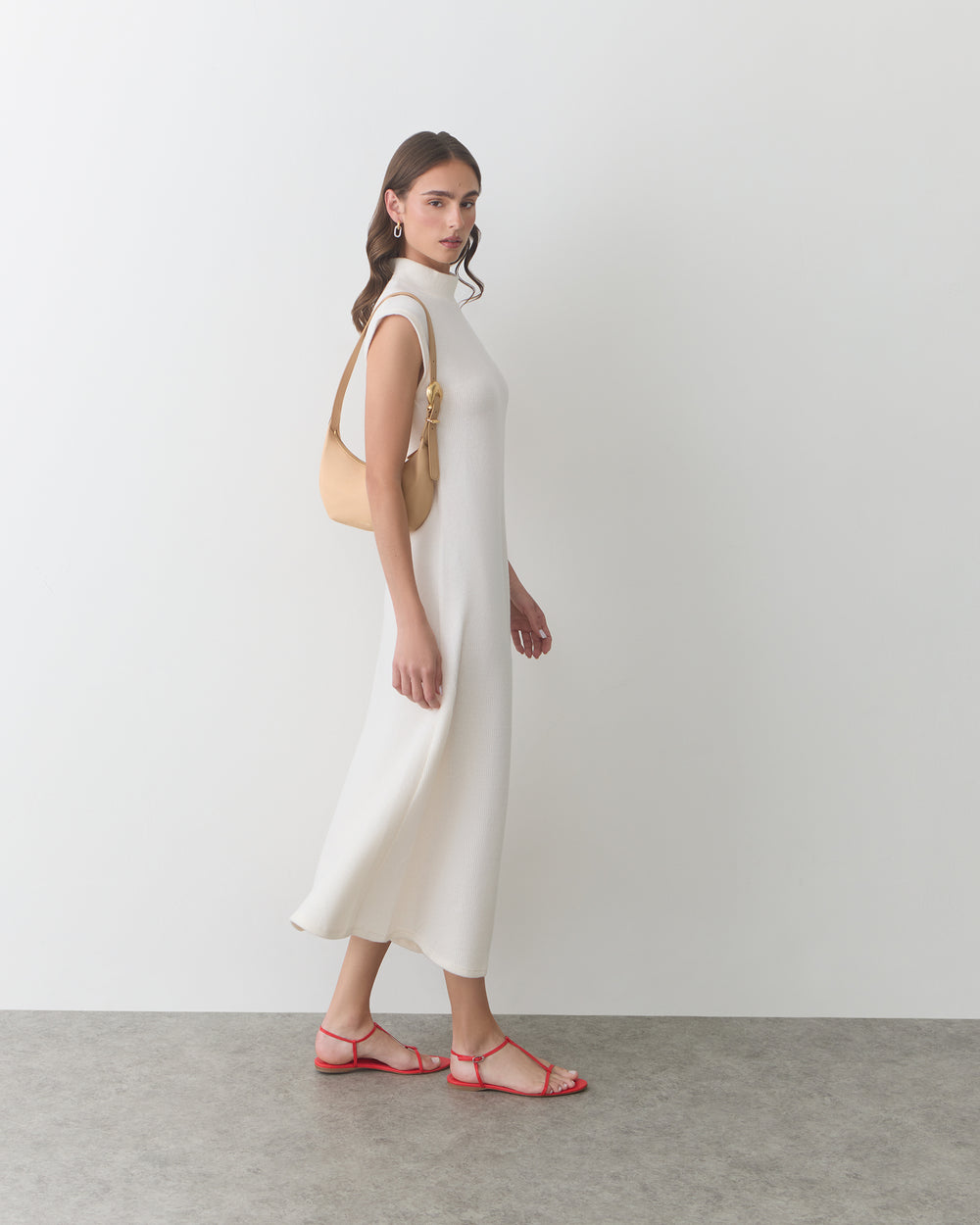 Person in long dress carrying a shoulder bag and wearing sandals.