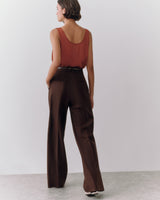Person in sleeveless top and wide-leg pants standing on a plain background.